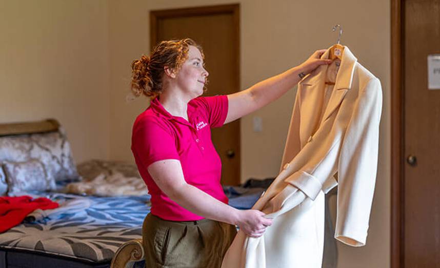 Estate sale specialist inspecting and pricing clothing during a Bethesda estate sale preparation