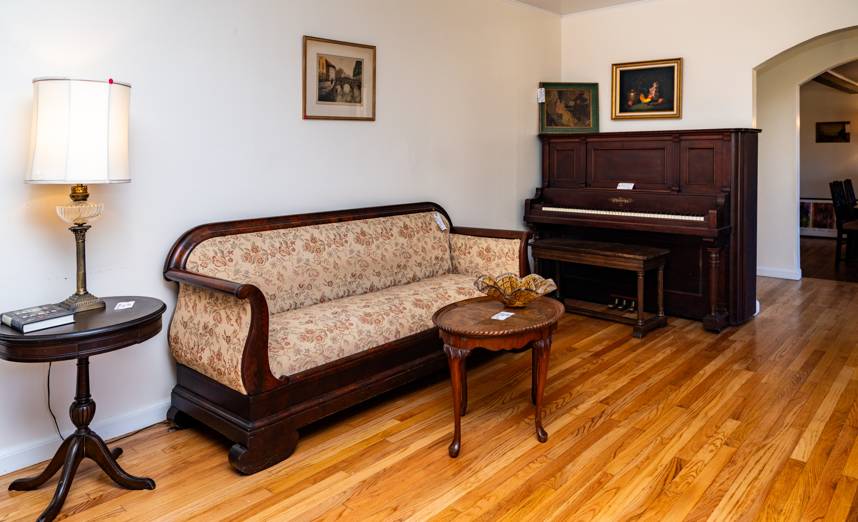 Antique sofa and upright piano staged for a Bethesda estate sale by Caring Transitions