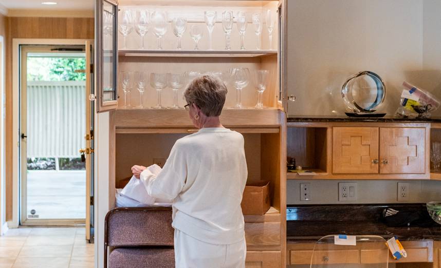 Sorting through china and crystal in a built-in cabinet during a Rockville estate cleanout